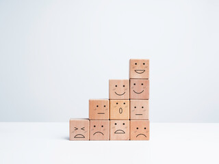 Business growth steps with happy and sad emotions on emoticon faces arrange on wooden blocks isolated on white background, minimal style. Satisfaction, evaluation, rating survey concept.