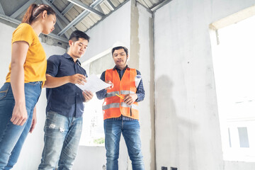 Fototapeta premium Young asian couple checking house with foreman engineering home inspection building house Walk home inspection looking pointing construction for check building home on job site to construction 2021