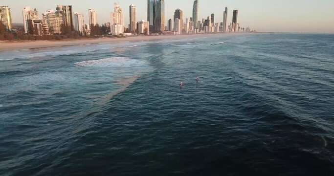 Drone aerial pan up with stand up paddle boarders on ocean during sunrise