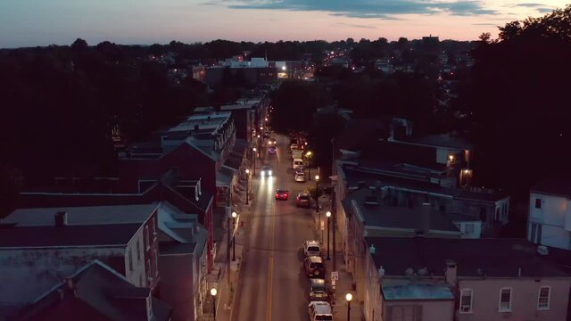 Sunset, sunrise with cars driving on American urban city street at night. Residential row houses and homes. Aerial view.