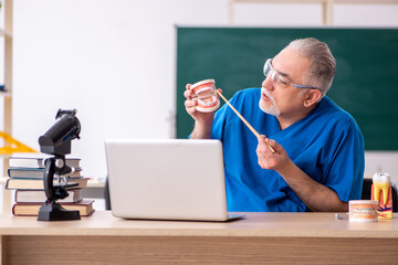 Old male doctor dentist in telestudying concept