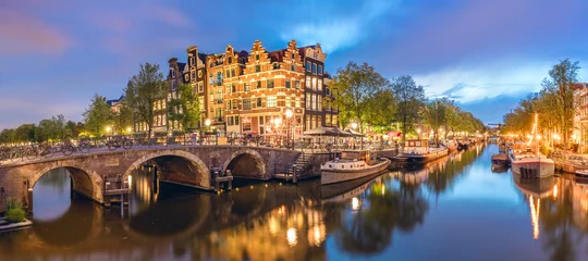 Foto op Aluminium Amsterdam, Netherlands. Panorama of the historic city center of Amsterdam. Traditional houses and bridges of Amsterdam small town. A romantic evening and a bright reflection of houses in the water.  © Taiga