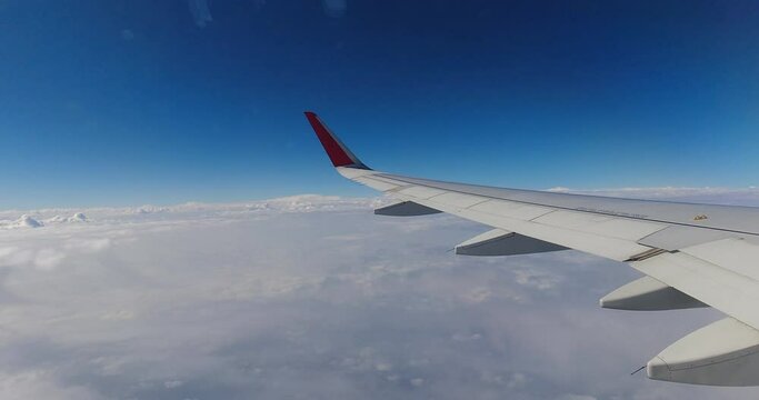 Blue sky hyperlapse plane wing seen through window above sea of clouds