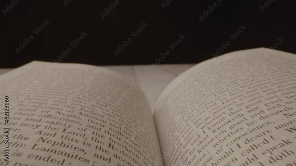 Poster a camera shot floating across an open book with a black background and the book is later closed