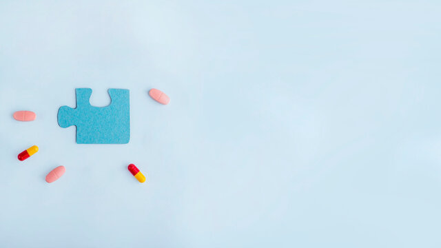 Blue jigsaw puzzle pieces with different pills and medicines. Concept of Neurological Disease Treatment : Autism, Alzheimer's, Dimension. Copy space for text. Awareness day. Supportive and Acceptance.