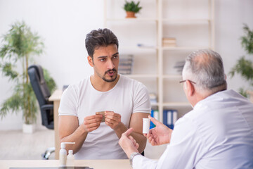 Old male doctor suggesting pills to young male patient