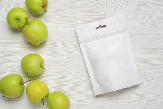 White plastic pouch bag with apples on wood table. 3d rendering.