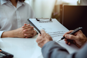The boss signs the resignation letter to the female employee.