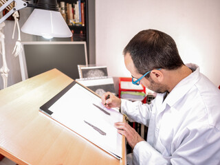 Fototapeta na wymiar Artist drawing at the work table in his painting studio. Selective focus