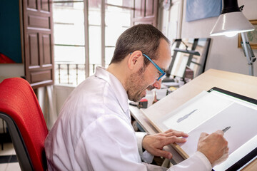 Artist drawing at the work table in his painting studio. Selective focus