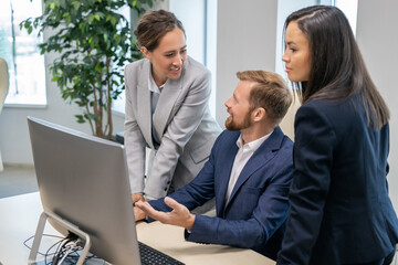 Young successful businesspeople in formalwear discussing presentation in front of computer