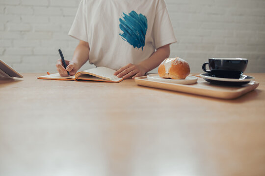 Young woman writing in notebook in coffee shop