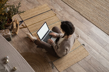 Aesthetic top view of woman sitting on carpet and work on laptop computer in cozy comfortable home...