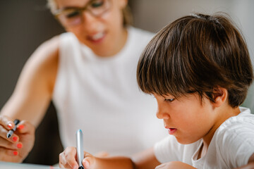 Preschool boy doing school education assessment test. Psychologist asking a questions and preschool boy writing answers.