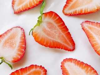 Pieces of half red strawberry are on some smoothie yogurt 