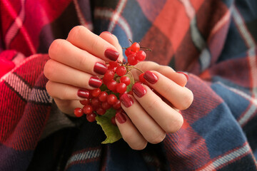 Stylish red female nails. Hands Holding Red Currants. Modern Beautiful manicure. Autumn winter nail...