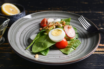 Plate with fresh salad and egg on dark wooden background