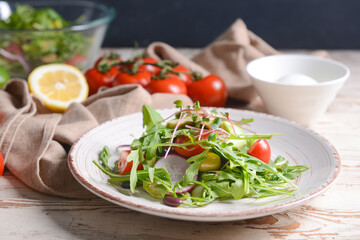 Plate with delicious salad on light wooden background