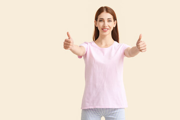 Young woman in modern t-shirt showing thumb-up on color background