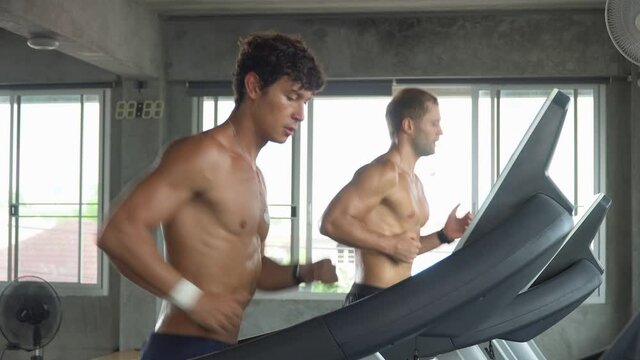 group of two muscular man running on treadmill  in fitness gym at sport club . male friend workout and talking together. Shirtless sport guy Exercise on running Machine. bodybuilder cardio training