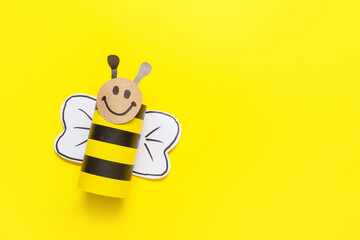 Figure of bee made of cardboard tube for toilet paper on yellow background