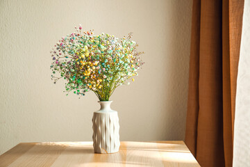 Vase with beautiful gypsophila flowers on table in room