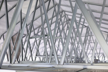 Fototapeta premium Structure of steel roof frame for building construction closeup