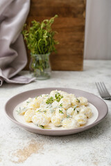 Plate of delicious gnocchi with creamy sauce on table