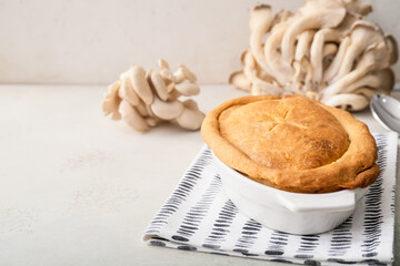 Baking dish with tasty mushroom pot pie on light background