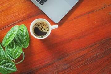 Coffee and laptop on wooden desk.