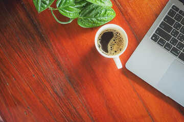 Coffee and laptop on wooden desk.
