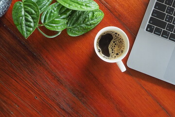 Coffee and laptop on wooden desk.