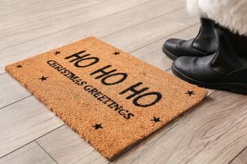 Door mat with Christmas greeting and Santa shoes on floor