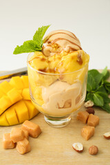 Bowl of delicious ice cream balls with caramels and mango on light background