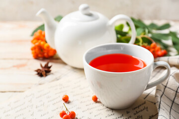Cup of tasty rowan tea on table, closeup