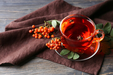 Cup of delicious rowan tea and berries on wooden background - obrazy, fototapety, plakaty