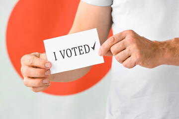 Man holding paper with text I VOTED against flag of Japan