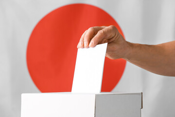Voting man near ballot box against flag of Japan