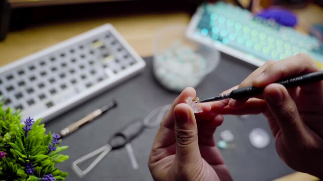 Footage of a person lubing linear switch for custom build mechanical DIY keyboard.
