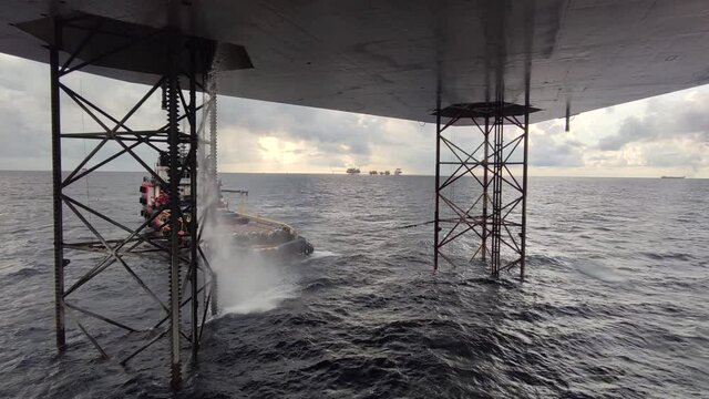 View Underneath Jack Up Drilling Rig In The Ocean with a supply boat and a central processing platform
