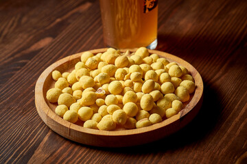 The classic beer snack is salty, roasted peanuts on a wooden plate. Food pub