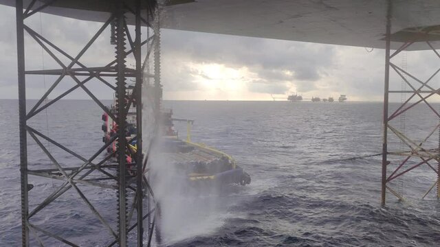 View Underneath Jack Up Drilling Rig In The Ocean with a supply boat and a central processing platform
