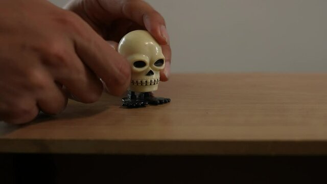 young man winding up  wind-up toy skull jumping
