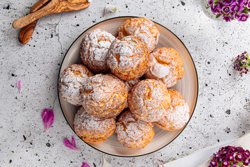 Fresh baked choux pastry cakes with powdered sugar