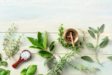 Cooking with herbs. A culinary design template with salt, pepper and aromatic herbs, overhead flat lay shot on a rustic wooden background