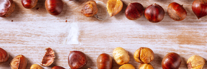 Chestnut panorama, shot from the top on a rustic wooden background. Autumn panoramic banner with a...