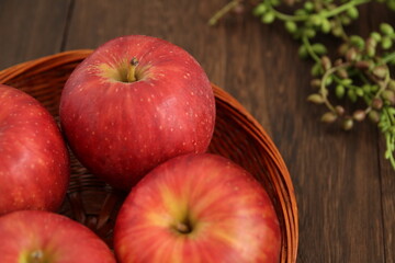 木製テーブルの上のバスケットに入った複数のりんご