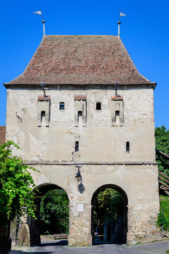 Large old white painted stone tower in the historical center of the Sighisoara citadel, in Transylvania (Transilvania) region of Romania, in a sunny summer day.