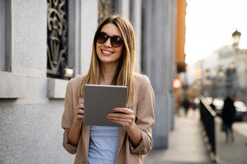 Fototapeta premium Beautiful young success woman with coffee using digital tablet against urban city background.