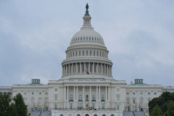 Impressive historic Capitol building with dome and columns in green tree park in Washington DC, D....